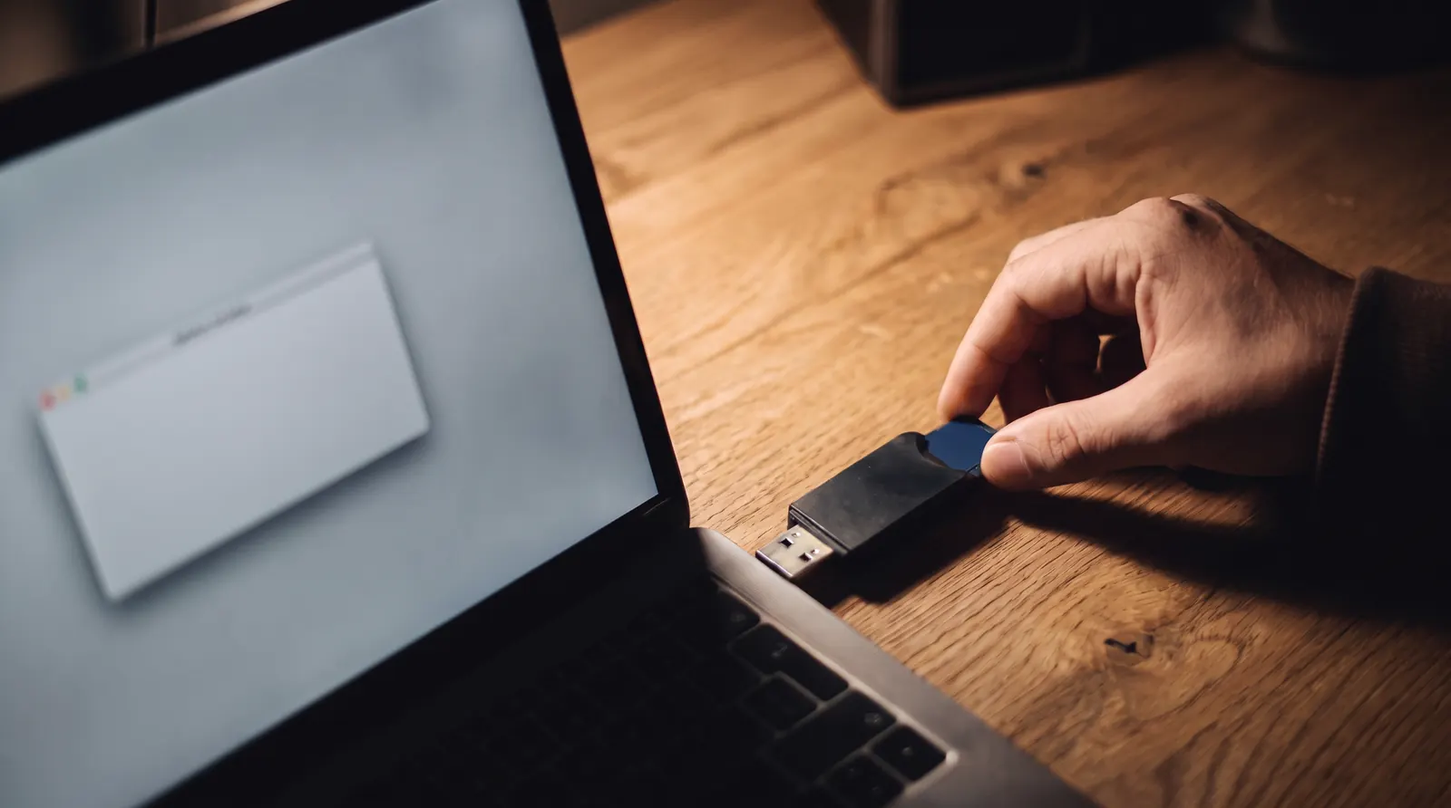 A memory card going into a card reader beside a laptop