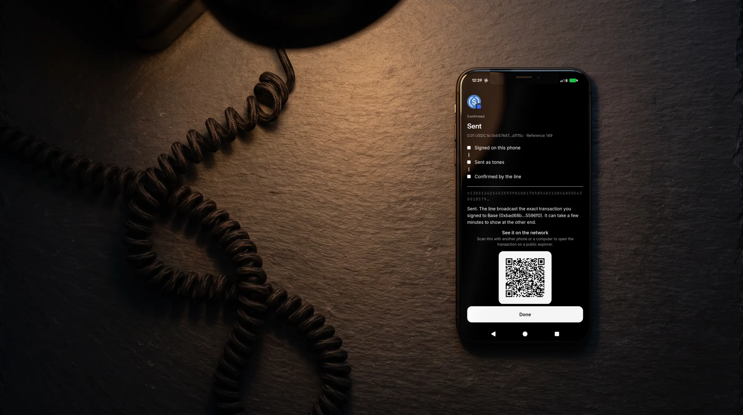 A phone lying on a slate desk at night beside a coiled telephone cord, showing the TELRPC Wallet's Sent screen: 0.01 USDC confirmed on Base